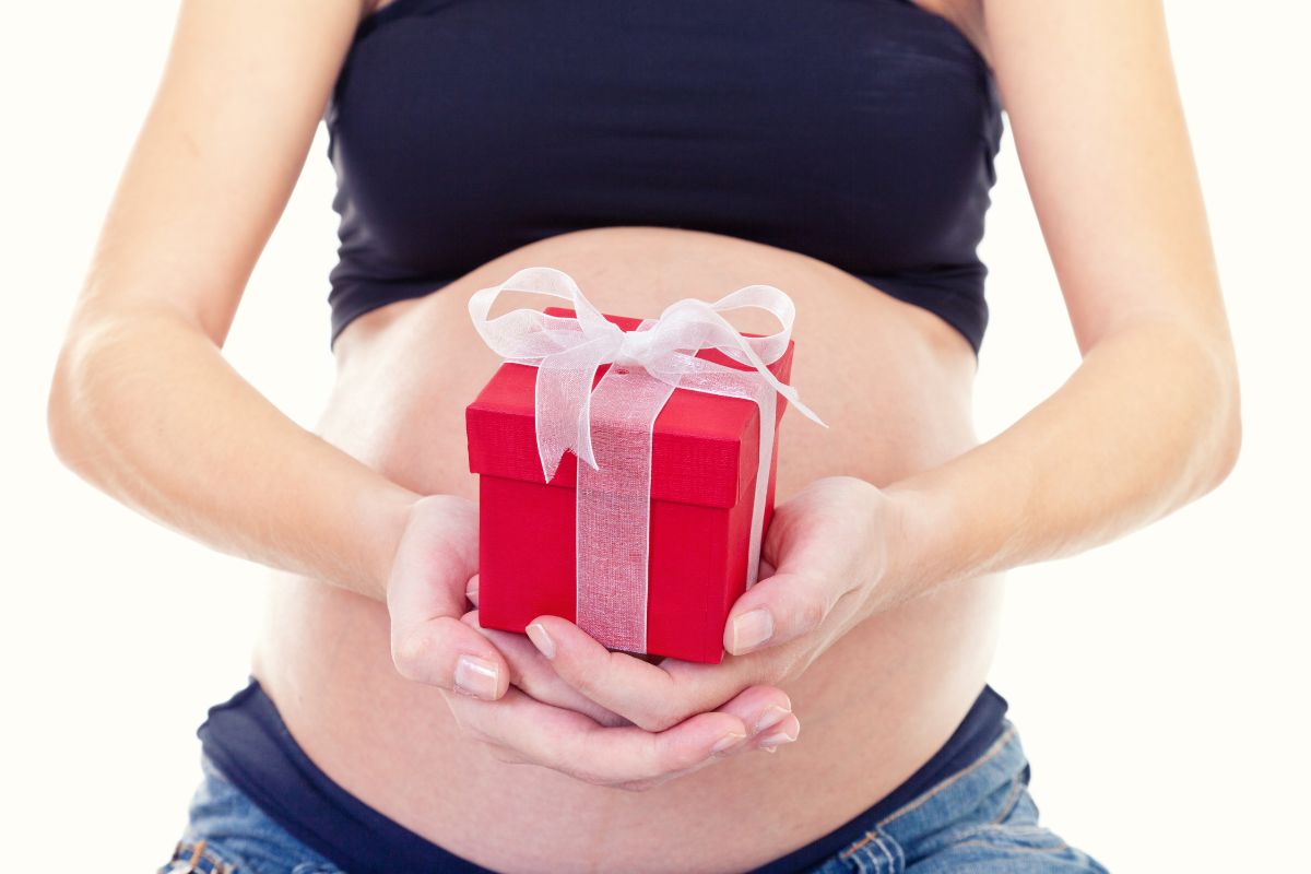 Une femme enceinte porte un cadeau devant son ventre