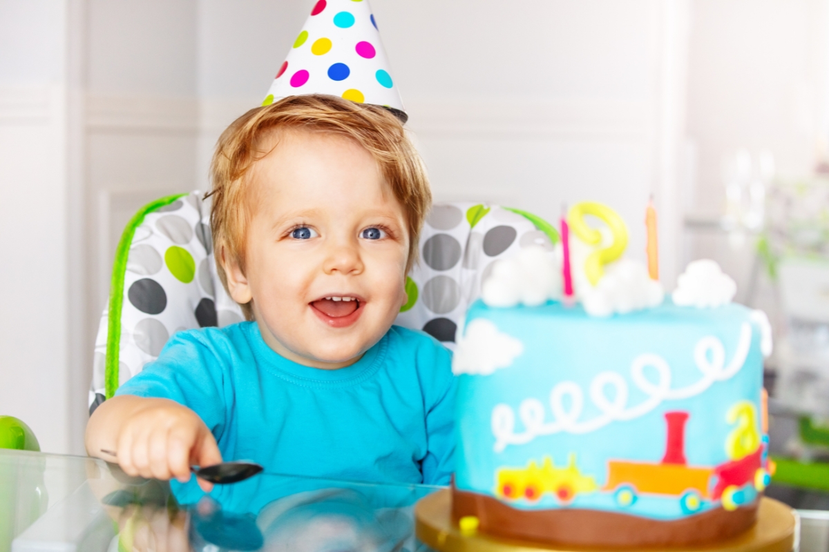 bébé de 2 ans devant son gâteau d'anniversaire