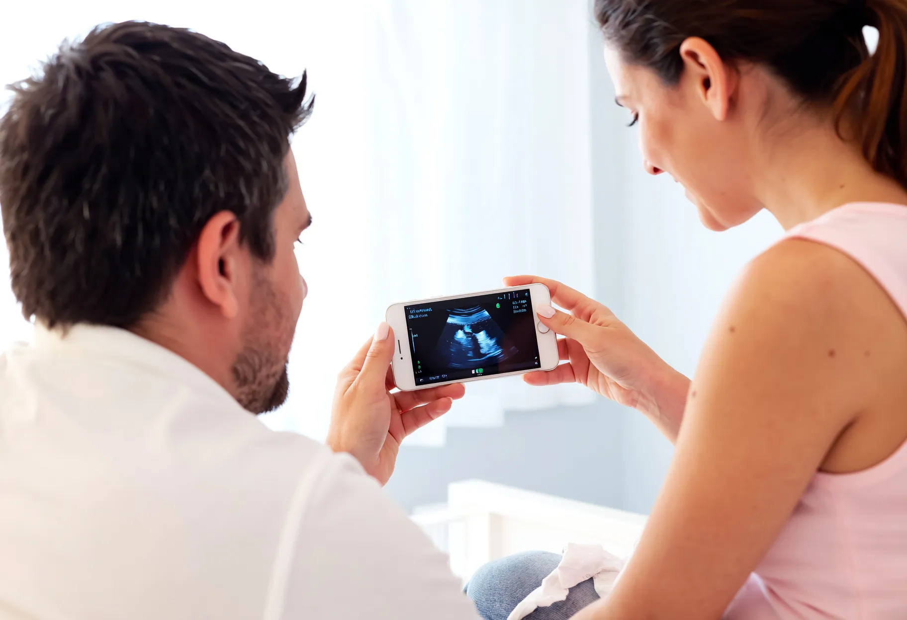 Futur papa et future maman découvrant ensemble une échographie sur tablette