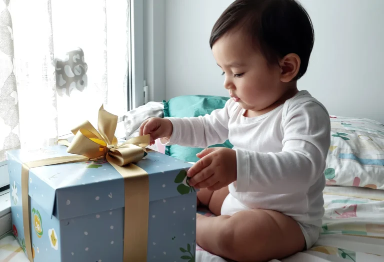 bébé de 18 mois qui reçoit un cadeau d’anniversaire avec émerveillement
