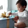 bébé de 18 mois qui reçoit un cadeau d’anniversaire avec émerveillement