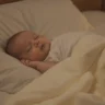 Bébé endormi paisiblement dans son lit sans gigoteuse, ambiance douce et rassurante.