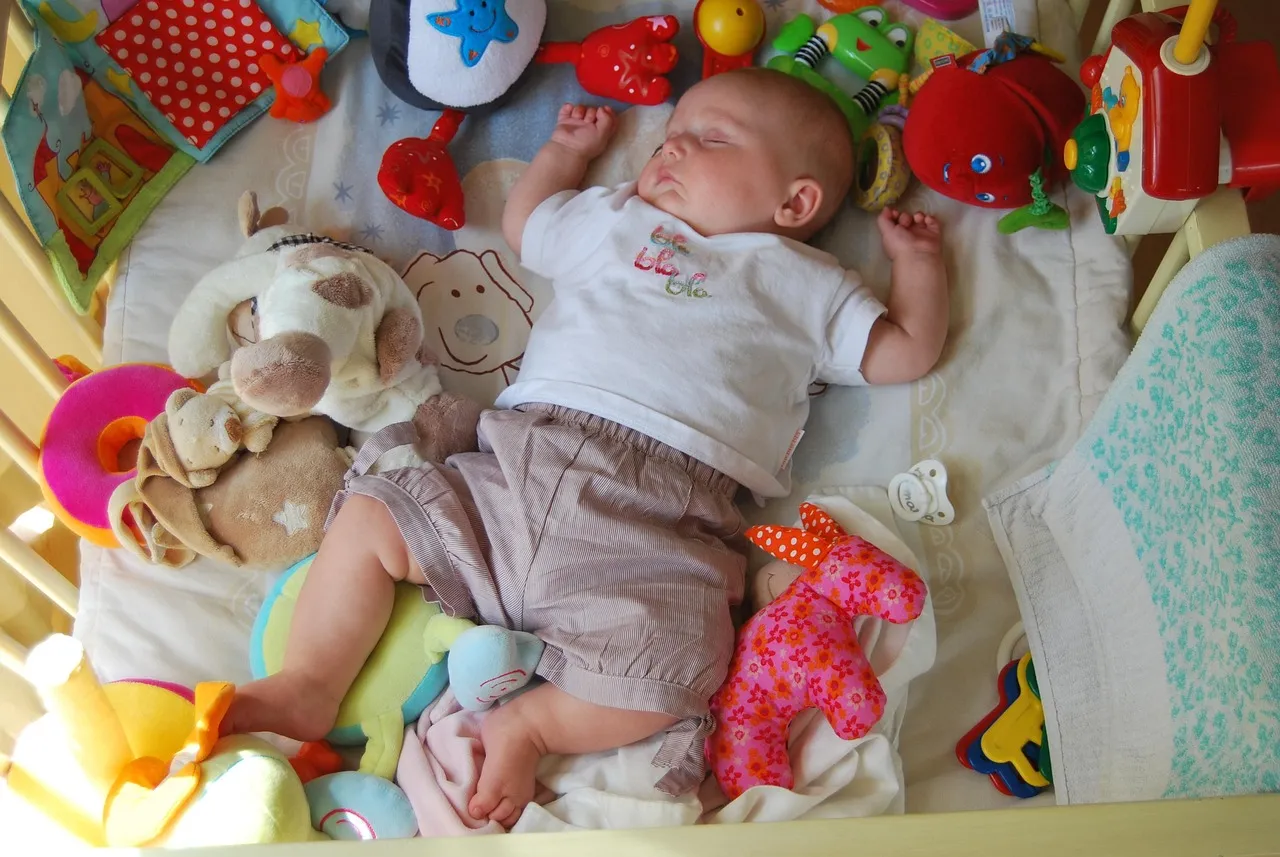 Bébé endormi profondément dans son lit entouré de jouets colorés