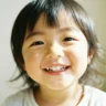 Enfant souriant montrant toutes ses dents de laits, derriere lesquels poussent dents definitives