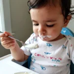 Un bébé d'un an mange une cuillere creme fraiche