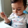 Un bébé d'un an mange une cuillere creme fraiche